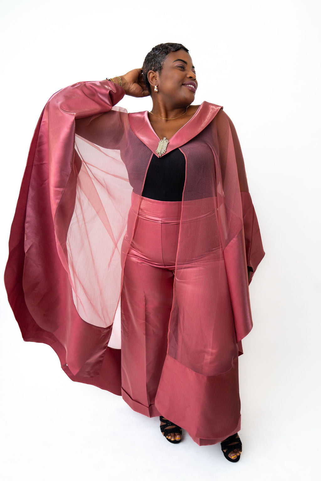 Woman wearing a pink outfit with a sheer overlay on a white background