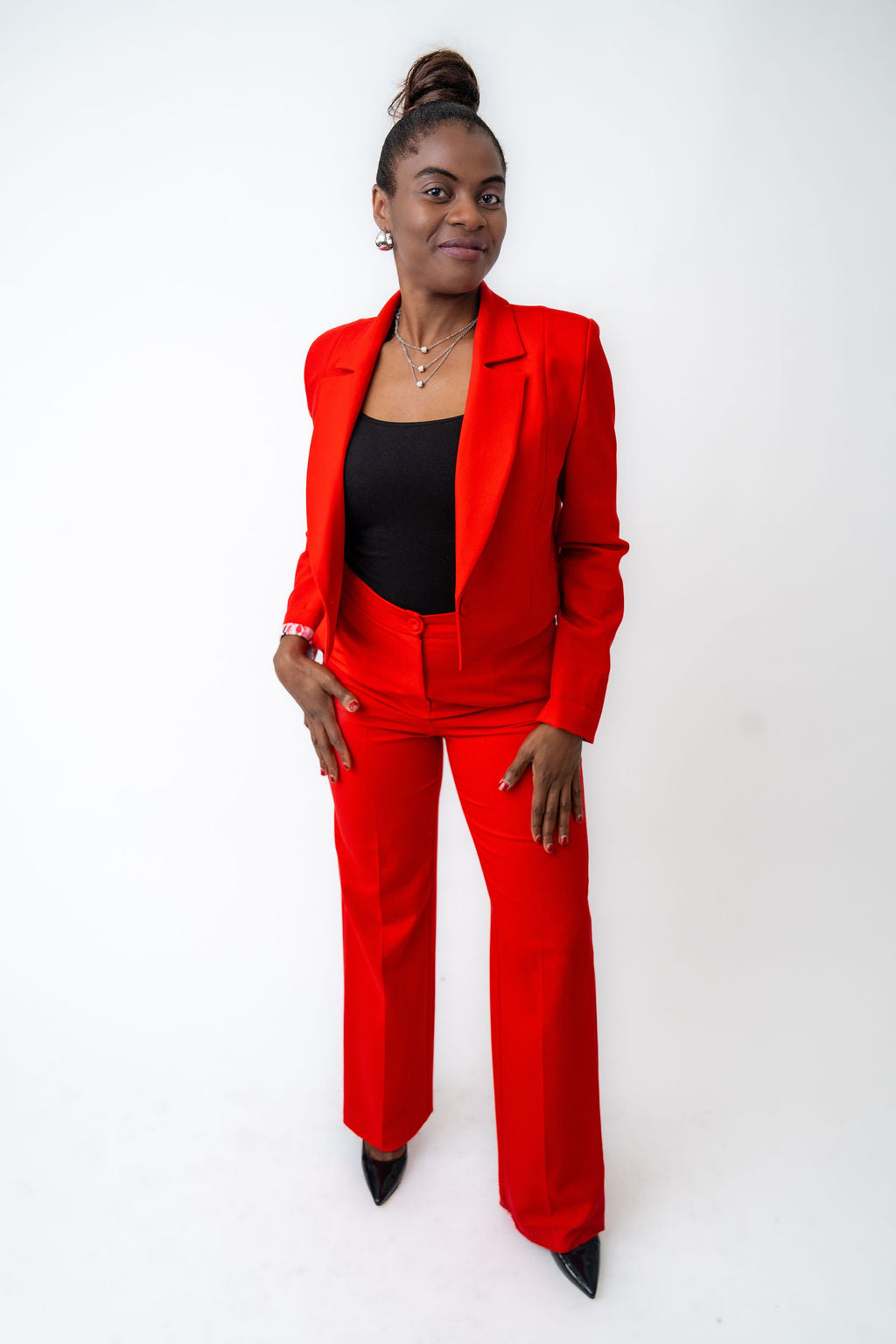 Woman wearing a red suit with a black top on a white background
