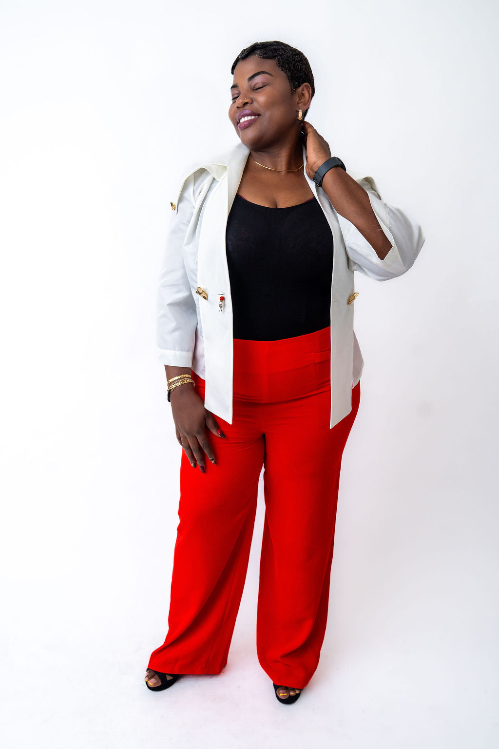 Woman wearing a white jacket, black top, and red pants on a white background