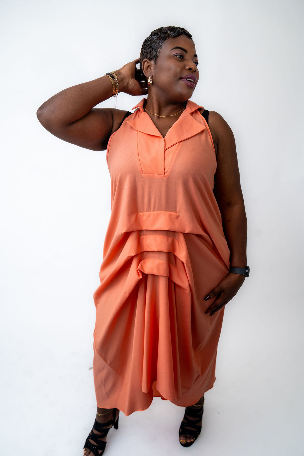 Woman wearing a peach-colored sleeveless dress against a white background