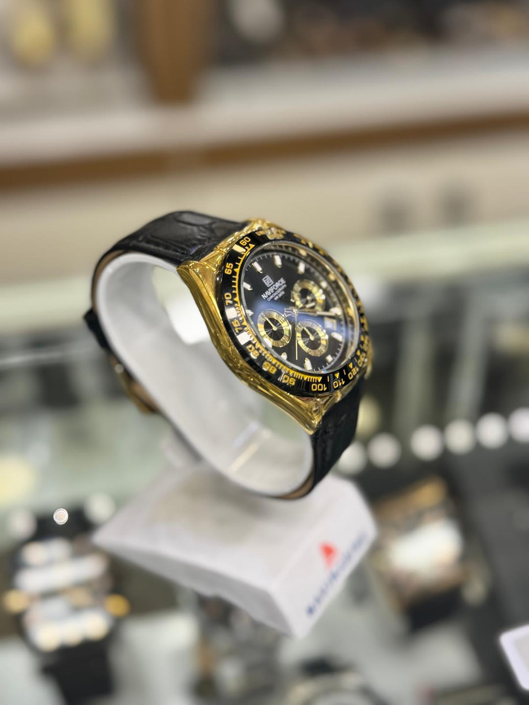 Gold and black watch on display with a blurred background