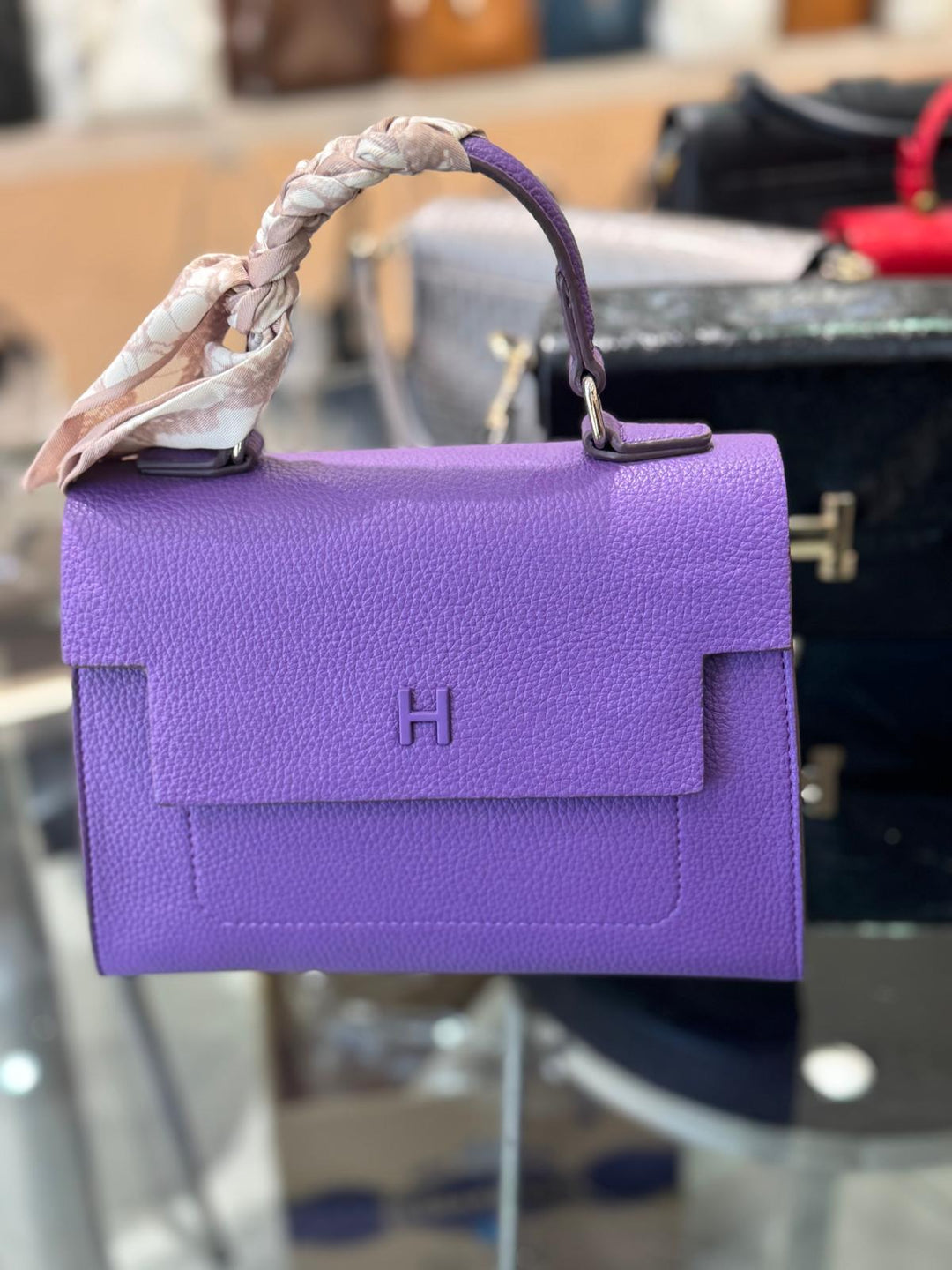 Purple handbag with a visible brand logo on a blurred background