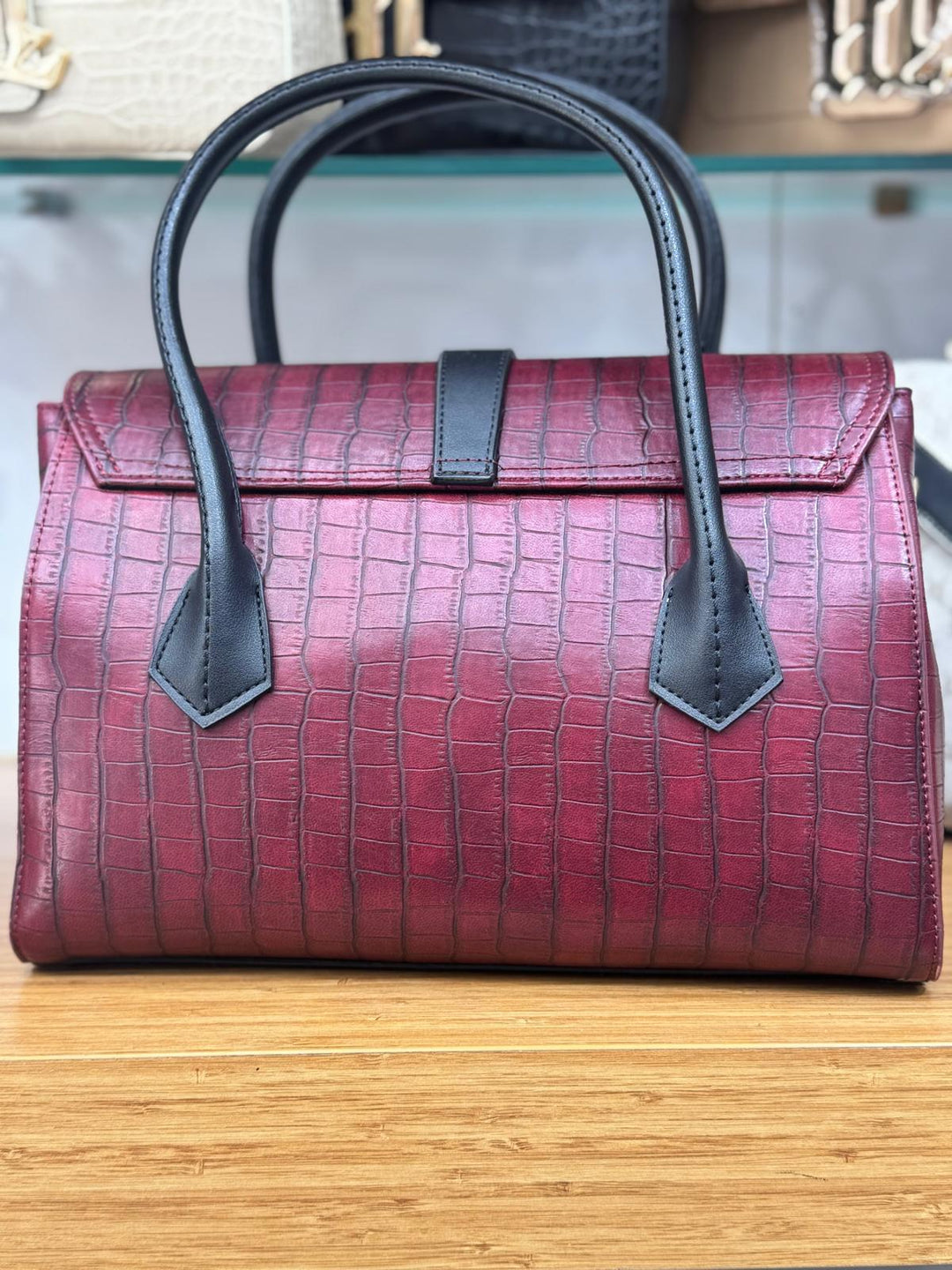 Red handbag with black handles and accents on a wooden surface